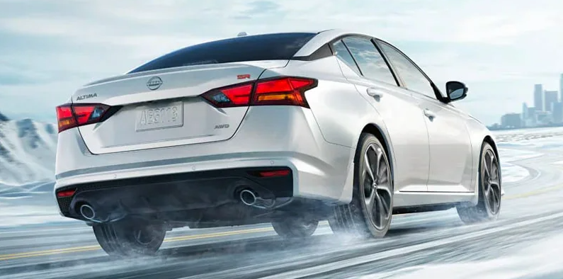 A white 2025 Nissan Altima driving down a snowy road.