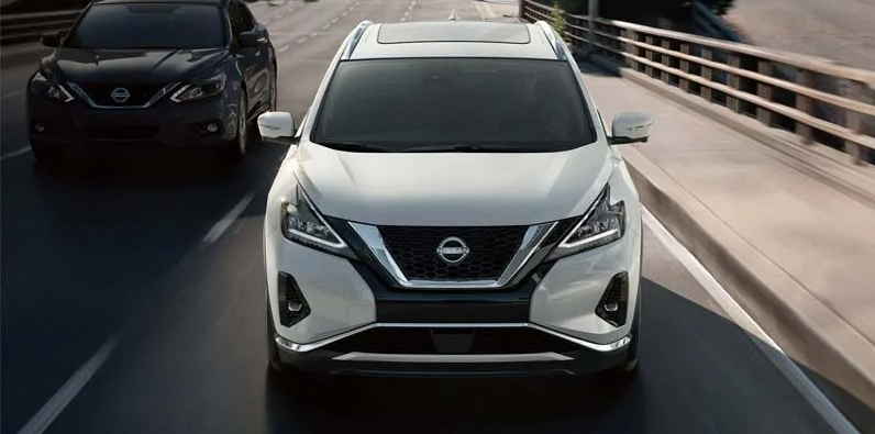 A white Nissan Murano driving down the road. 
