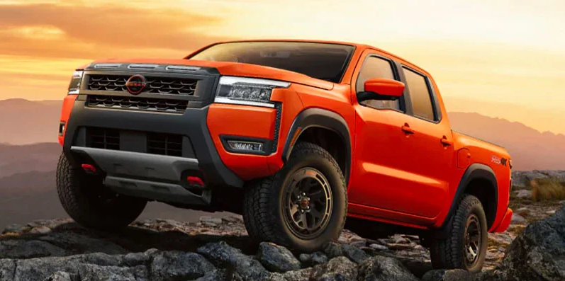 A red 2025 Nissan Frontier parked up on a rocky cliff.