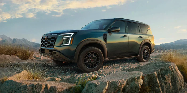 Nissan Armada parked on a sandy patch of land.