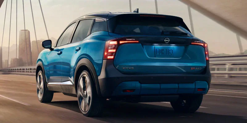 A blue 2025 Nissan Kicks driving across a bridge.