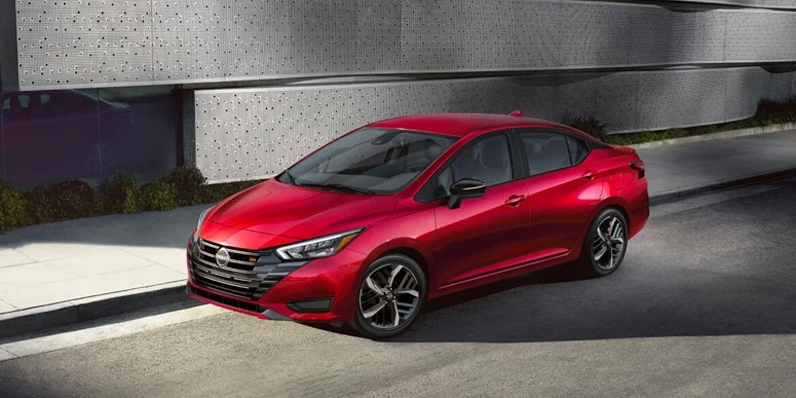 A red 2025 Nissan Versa driving down the road.