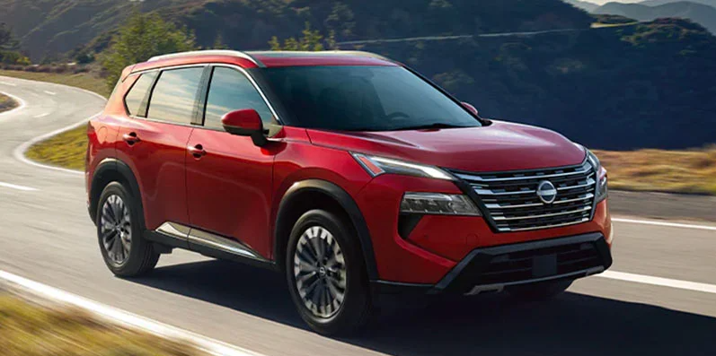 A photo of a 2025 Nissan Rogue driving down the road.
