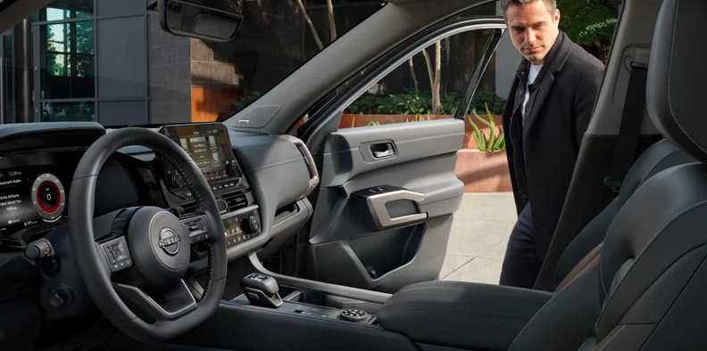 A photo of a man climbing in to the drivers side of a 2025 Nissan Pathfinder.