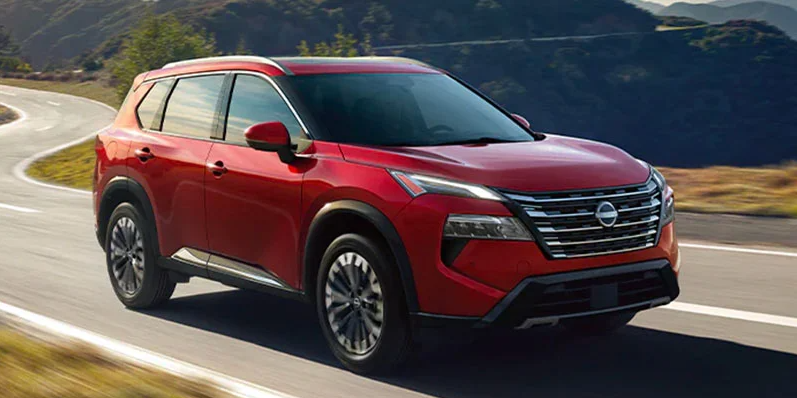 A red 2025 Nissan rogue driving down the road.