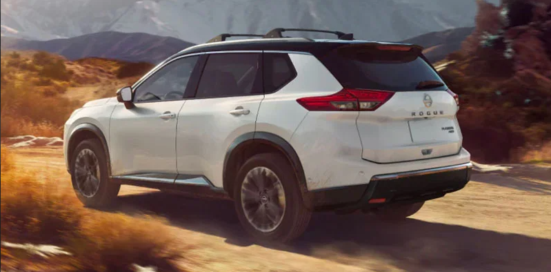 A photo of a 2025 Nissan Rogue driving down a dirt road.